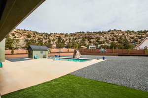 View of swimming pool featuring a water slide, a fenced backyard, an outdoor structure, a fenced in pool, and a patio area