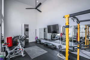 Exercise room with a towering ceiling, ceiling fan, and baseboards