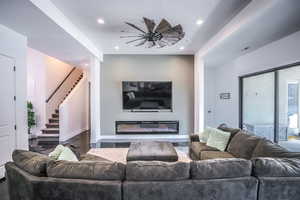 Living area featuring recessed lighting, stairway, a glass covered fireplace, wood finished floors, and baseboards