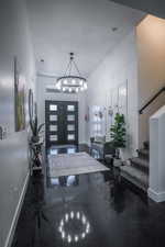 Foyer featuring a chandelier, french doors, baseboards, and stairs