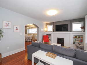 Living room featuring a fireplace with flush hearth, built in shelves and cabinets