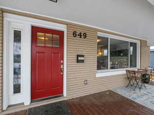 View of exterior entry featuring a porch and brick siding