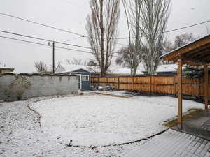 Fully fenced yard with snow covered plants and sod