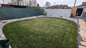 View of backyard with sod, flower beds with stones and slate stone path on chat gravel