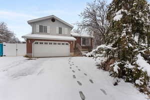 Tri-level home with a garage, brick, siding, fence, and a gate