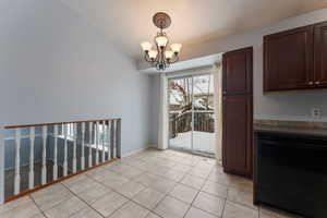 Dining area featuring an inviting chandelier, backyard access, and light tile patterned flooring