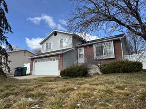 Split level home featuring an attached garage and brick siding