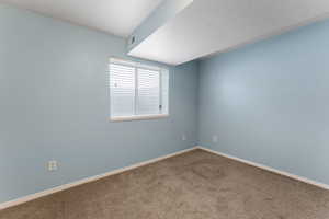 Carpeted spare room featuring visible vents, a textured ceiling, and baseboards