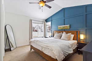 Bedroom with light colored carpet, vaulted ceiling, a textured ceiling, and a decorative wall