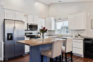 Kitchen featuring wine cooler, white cabinetry, stainless steel appliances, and butcher block countertops