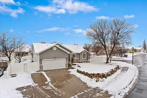 Single story home featuring stucco siding, an attached garage, fence, stone siding, and driveway