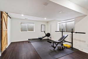 Workout room with a barn door, baseboards, wood finished floors, and recessed lighting