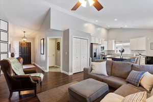 Living area featuring dark wood-style floors, recessed lighting, ceiling fan, high vaulted ceiling, and baseboards