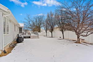 Yard covered in snow with a fenced backyard and a deck