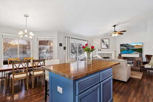 Kitchen featuring a center island, dark wood finished floors, a fireplace, hanging light fixtures, and blue cabinets