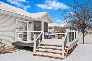 Snow covered property entrance with a wooden deck and fence