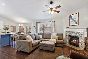 Living area featuring a textured ceiling, vaulted ceiling, dark wood-style flooring, and a tile fireplace