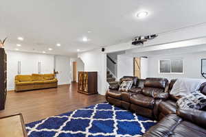 Living area with baseboards, stairway, wood finished floors, and recessed lighting