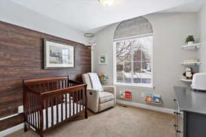 Carpeted bedroom with visible vents, wood walls, a textured ceiling, a nursery area, and baseboards