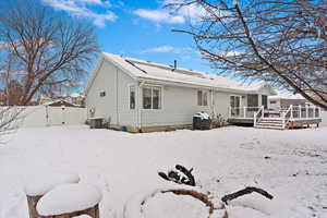 Snow covered house featuring a gate, fence, a wooden deck, and central AC unit