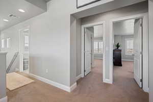 Corridor with a textured ceiling and light colored carpet