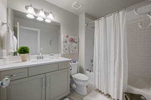 Full bathroom featuring toilet, shower / bath combination with curtain, and vanity