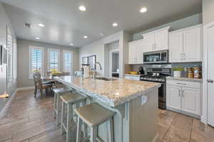 Kitchen with white cabinets, an island with sink, stainless steel appliances, and sink