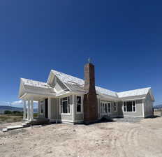 Back of house featuring covered porch and a chimney