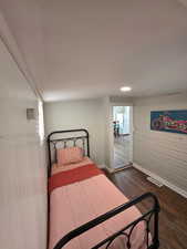 Bedroom featuring dark wood finished floors, visible vents, freestanding refrigerator, and baseboards