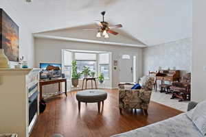 Interior space with light wood finished floors, wallpapered walls, baseboards, vaulted ceiling, and an accent wall