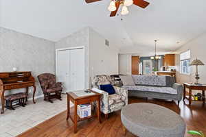 Living area with wood-type flooring, vaulted ceiling, and wallpapered walls