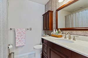 Bathroom featuring toilet, tile patterned floors, and vanity