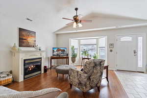 Living area featuring vaulted ceiling, lots of natural light, and wood finished floors