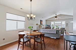 Dining space with large window, vaulted ceiling, baseboards, and wood finished floors