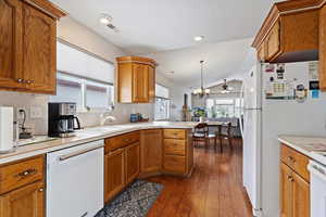 Kitchen with white appliances, a sink, light countertops, brown cabinets