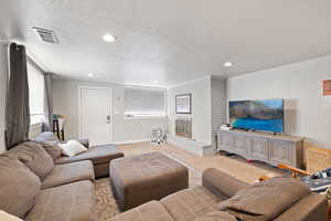 Large Side: Basement living room featuring baseboards, light colored carpet, a textured ceiling, a brick fireplace, and separate entrance