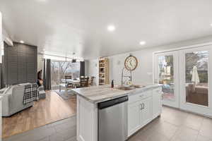 Large Side: Kitchen with light tile floors, white cabinetry, dishwasher, and an island with sink