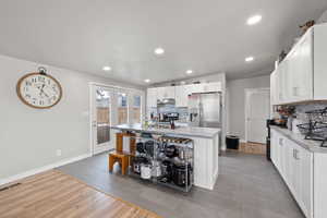 Large Side: Kitchen featuring French doors, appliances with stainless steel finishes, white cabinets, and under cabinet range hood