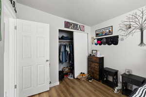 Smaller Side: Bedroom 1 with dark wood-style floors, a closet, and a textured ceiling