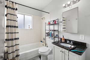 Smaller Side: Full bathroom featuring shower / bathtub combination with curtain, vanity, and toilet