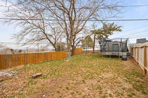 Smaller Side: View of yard featuring a fenced backyard, and a trampoline,