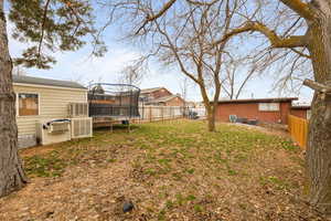 Smaller Side: View of fenced backyard with a trampoline