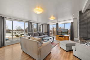 Large side: Living area with light wood-type flooring and floor to ceiling windows