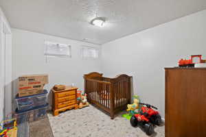 Large Side: Bedroom 5 featuring light colored carpet and a textured ceiling