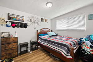 Smaller Side: Bedroom 1 featuring light wood-style floors and a textured ceiling