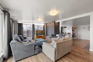 Large side: Living area with light wood-type flooring and floor to ceiling windows