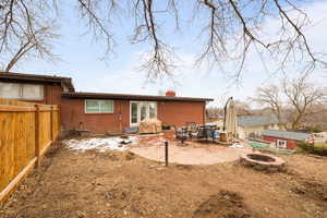 Large Side: Back of property with an outdoor fire pit, a fenced backyard, brick siding, a chimney, and a patio area