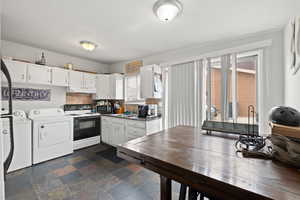 Smaller Side: Kitchen featuring electric range, white cabinetry, a sink, and separate washer and dryer, and sliding glass door.