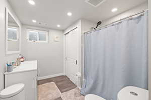 Large Side: Bathroom 2 with toilet, wood finished floors, vanity, and recessed lighting