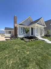 View of front of house featuring a chimney, a porch, and a front lawn